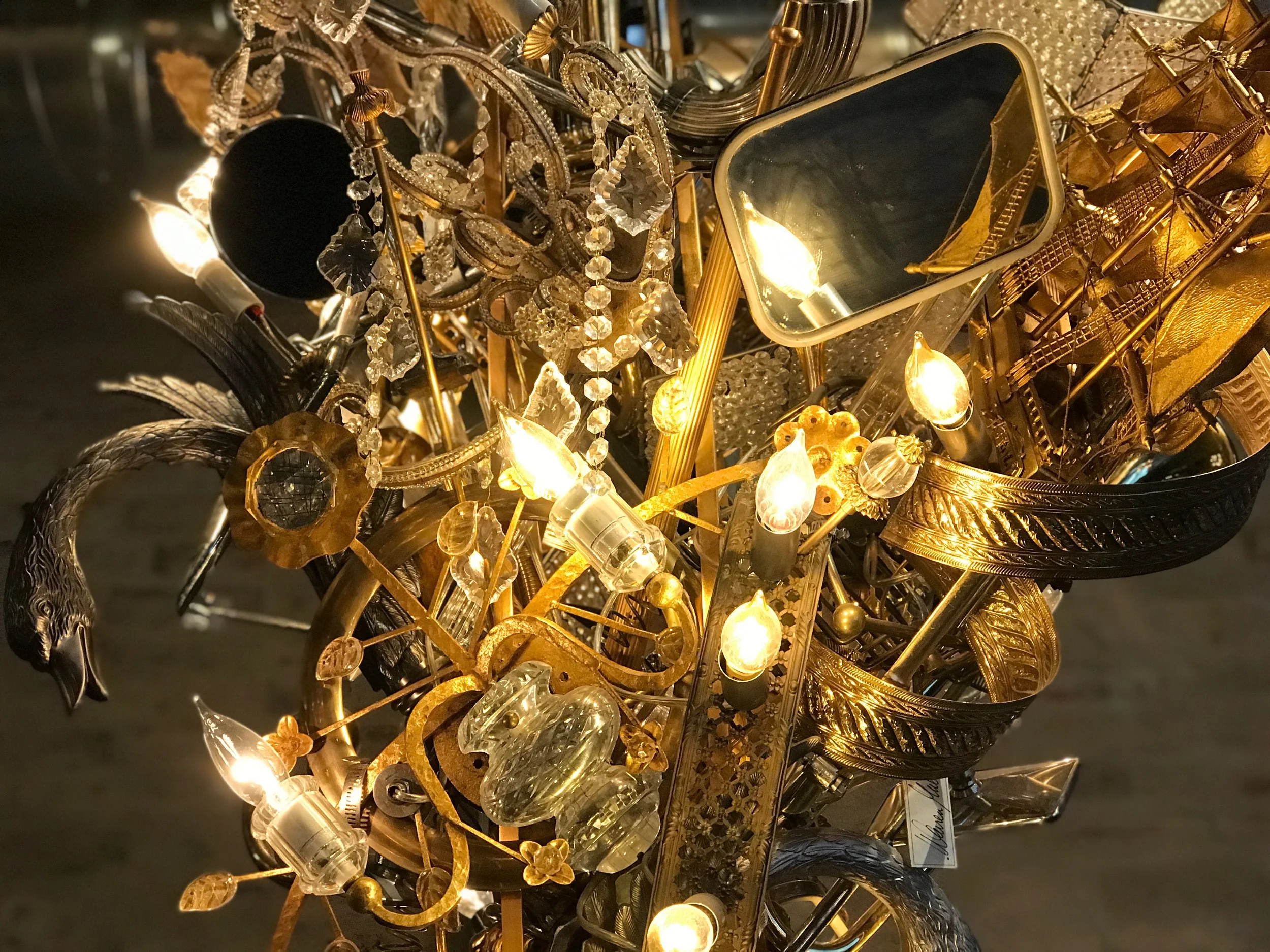  This work invites the viewer to trace gilded trails through gems, gold, and light . Mirrors reflect the work itself, the viewer, and the environment which expands the boundaries of the piece beyond its presence. 