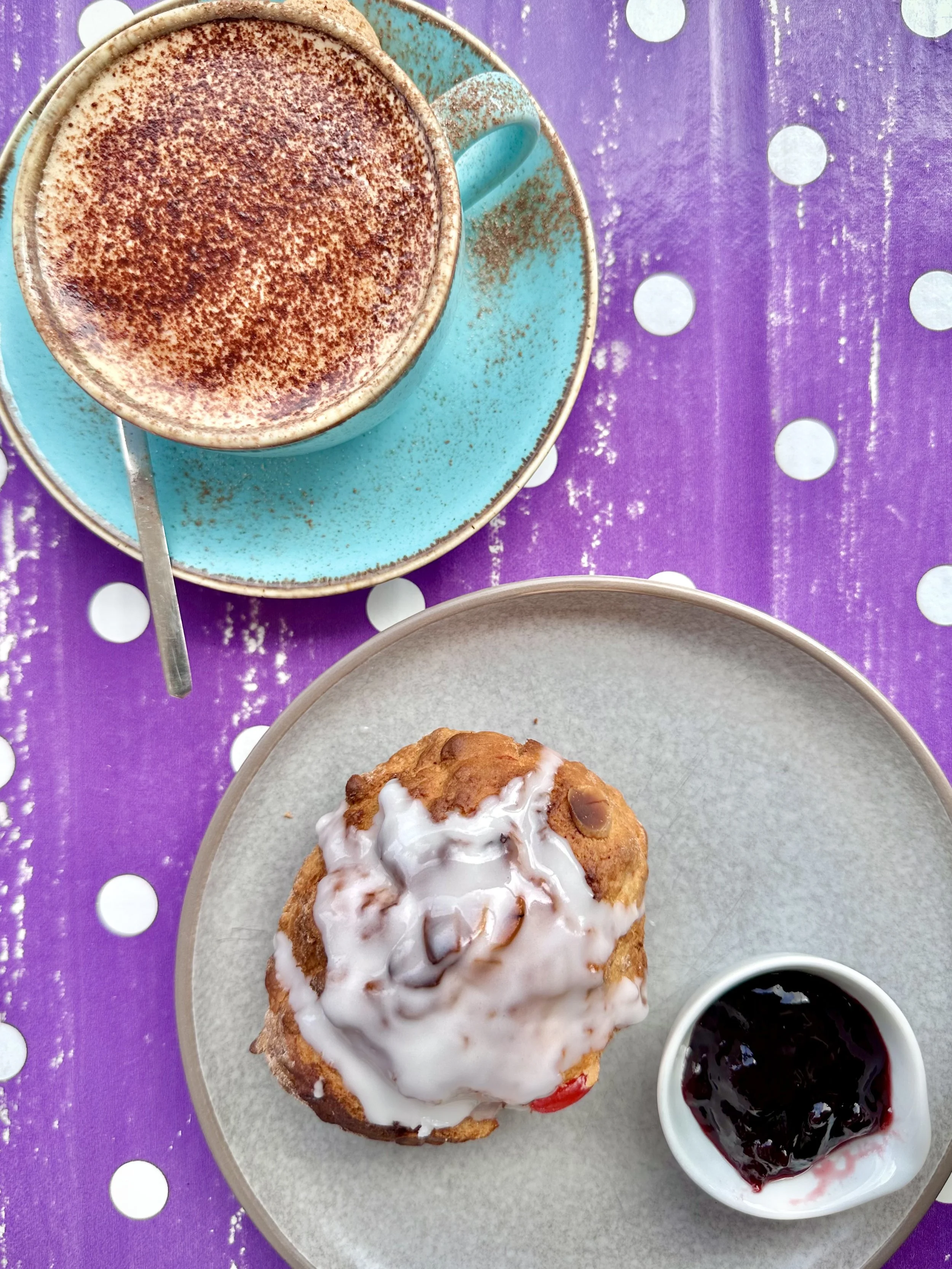 A scone on a plate next to a cup of coffee
