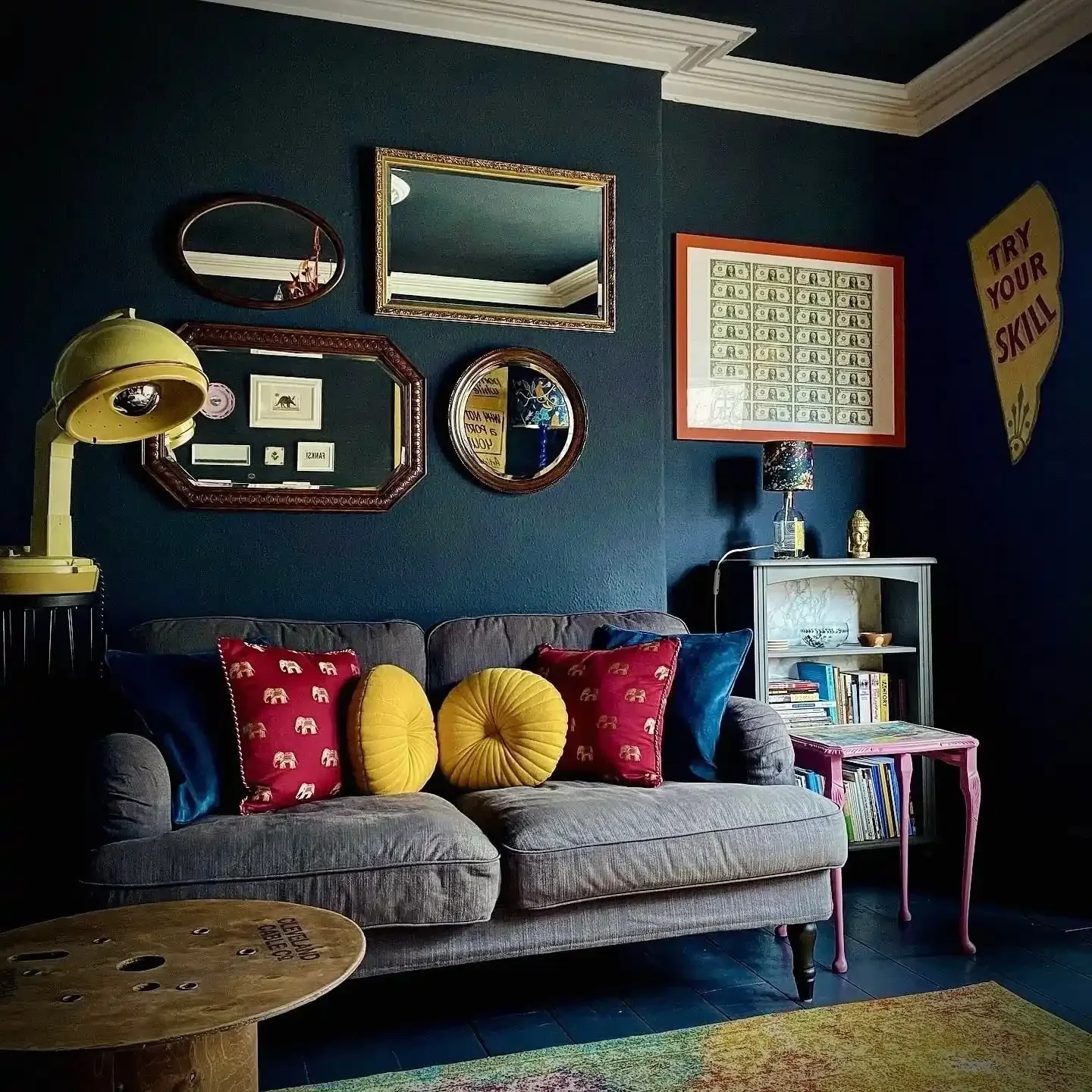 A lounge at Crafnant House B&B, with black walls, a grey sofa, cushions, and mirrors and art on the walls
