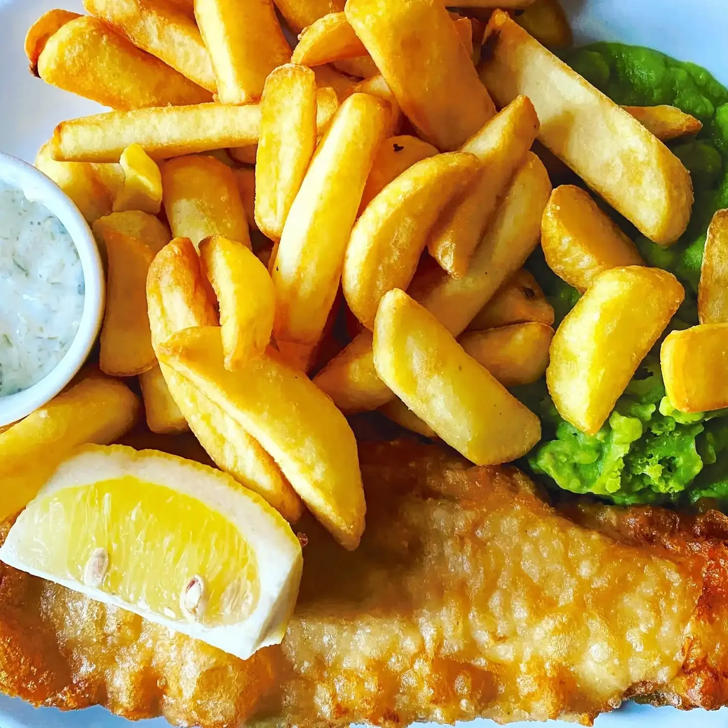 fish, chips and mushy peas seen from above with a slice of lemon