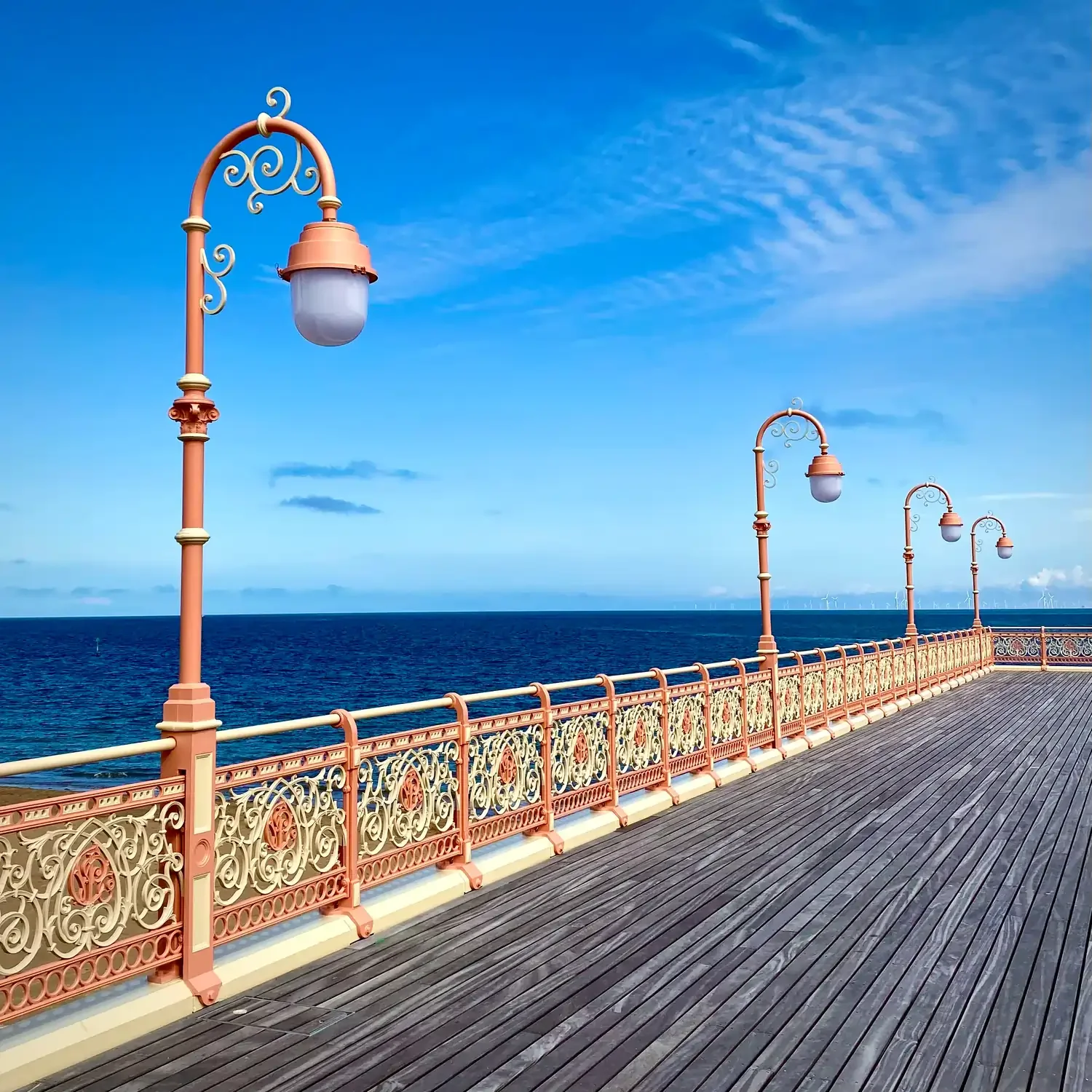 Victorian pier leading out to sea, painted peach and cream, with wooden slats on the floor