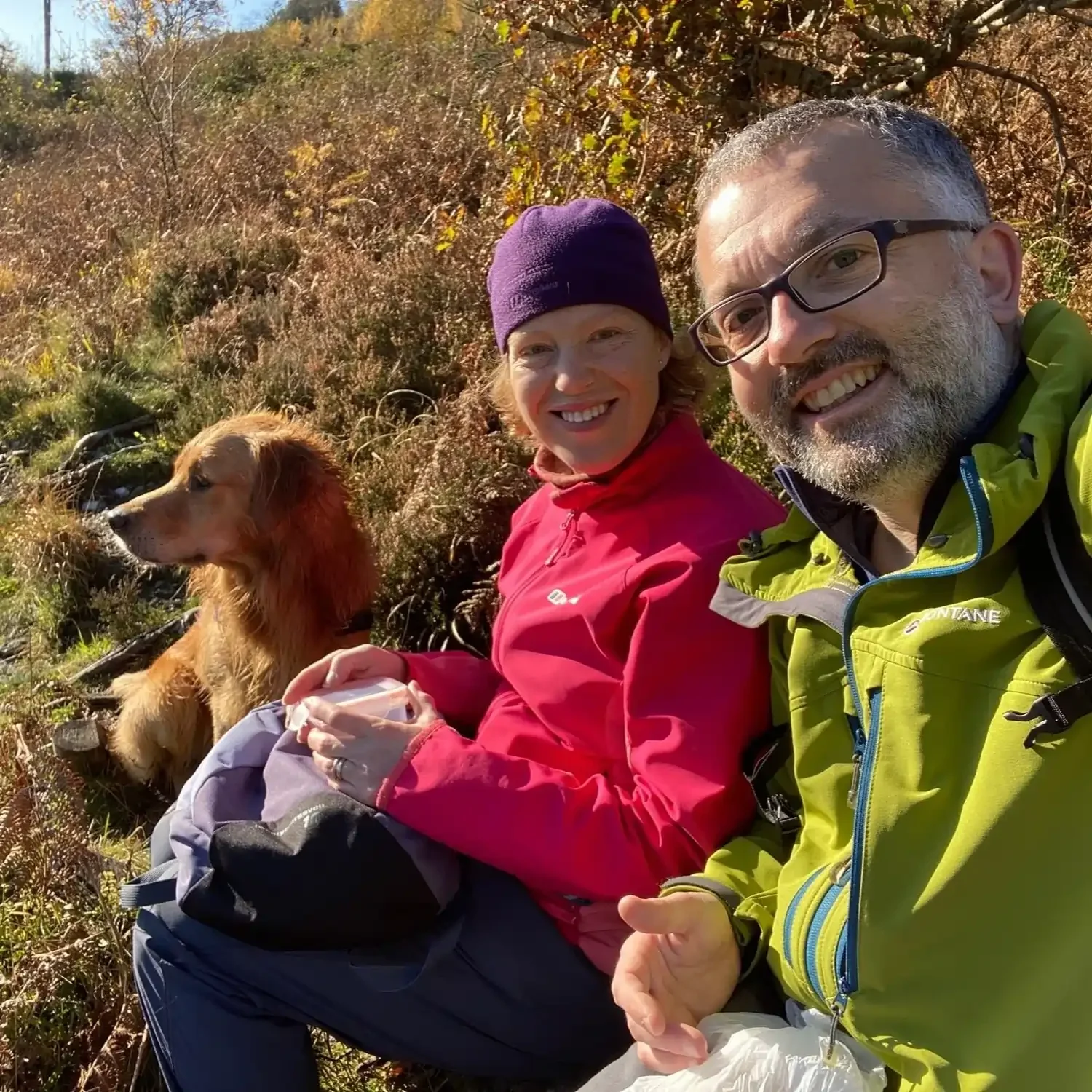 man, woman and dog looking at camera and smiling