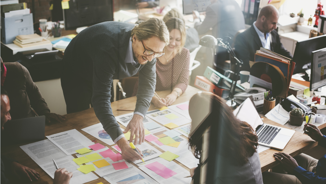 UX/UI designers collaborating on a whiteboard (with sticky notes, colored markers, story-boards, process-flow-charts, and concept sketches) for the ideation phase of a mobile app development and interface design project
