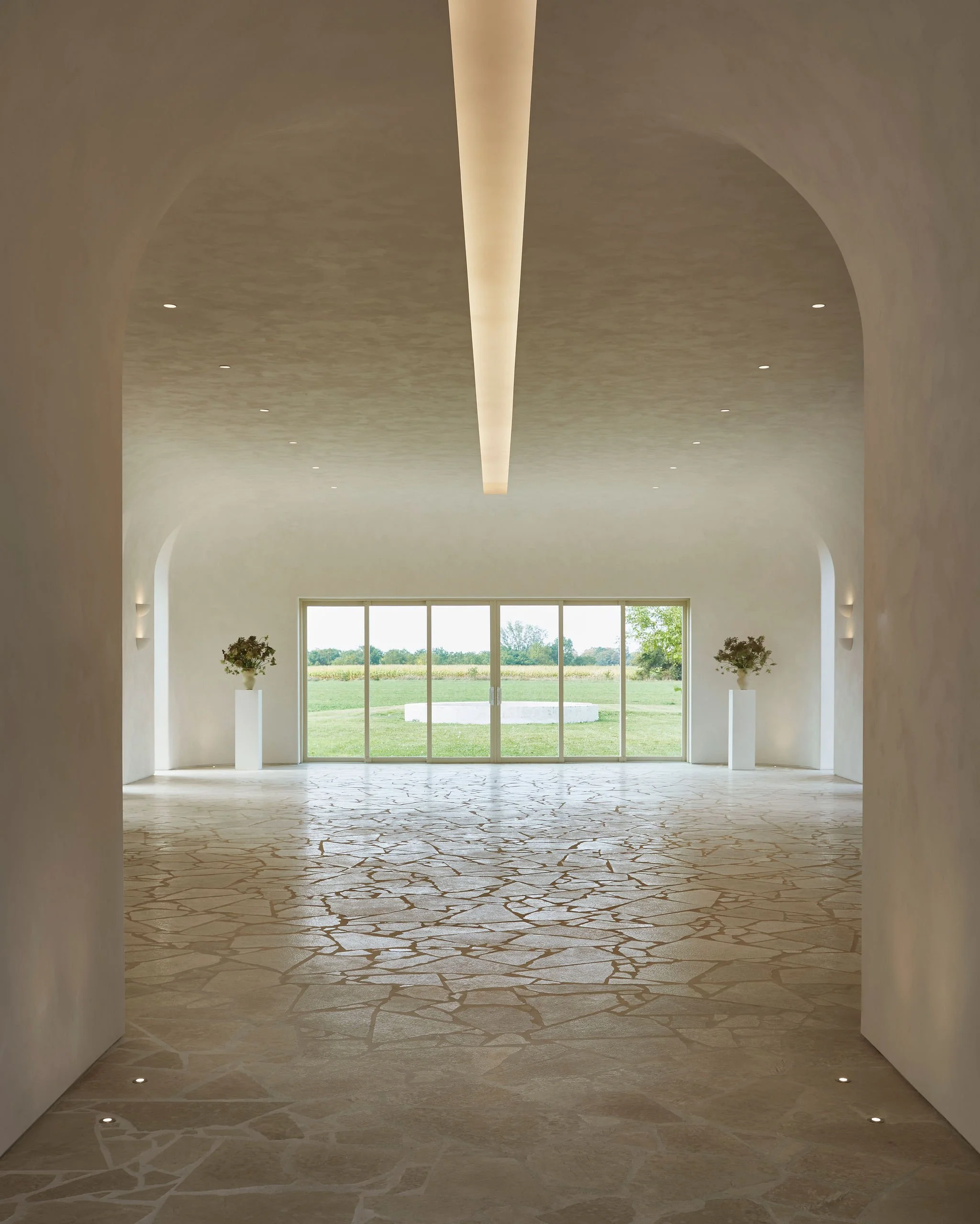 Main event space inside the Lune 1860 barn, with vaulted plaster ceiling, stone floor and views across the Ontario countryside.