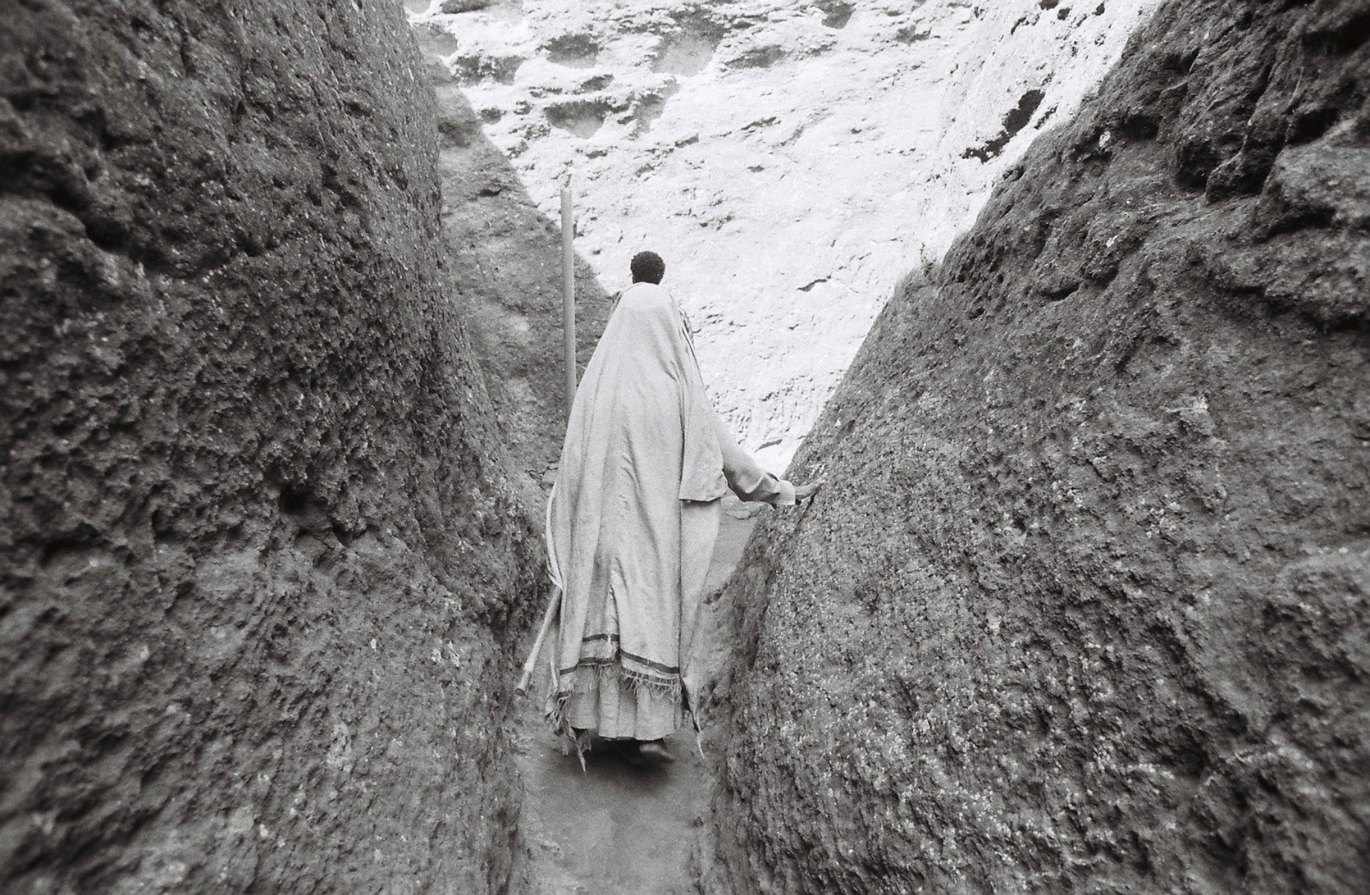 A pilgrim steadies herself as she navigates the narrow pathways within Lalibela.
