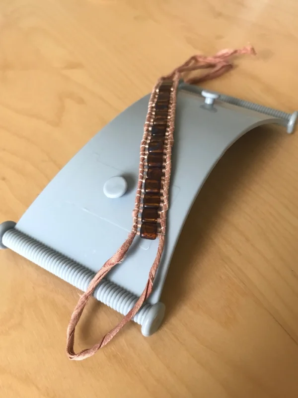 12. Turn the loom over. Remove the work from the loom by untying the ends.