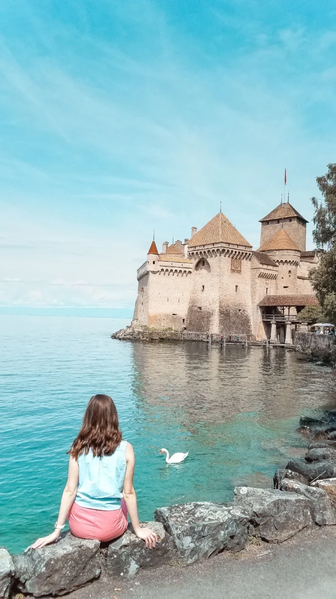 The Swiss castle of Chateau de Chillon is on Lac Lemon in Montreux, Switzerland. You can take a boat excursion on the lake to see the castle with a mountainous backdrop. #Switzerland #Travel #Castle #TravelBlog #Lake