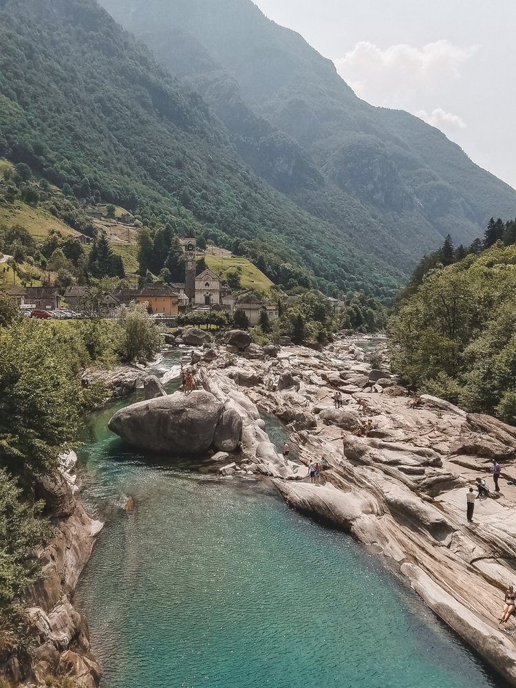 Valle Verzasca Switzerland has crystal clear waters with an emerald hue that flow along smoothed rocks.