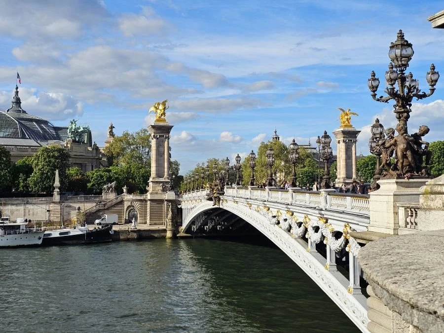 A bridge over the Seine River in Paris with black lamps and golden sculptures