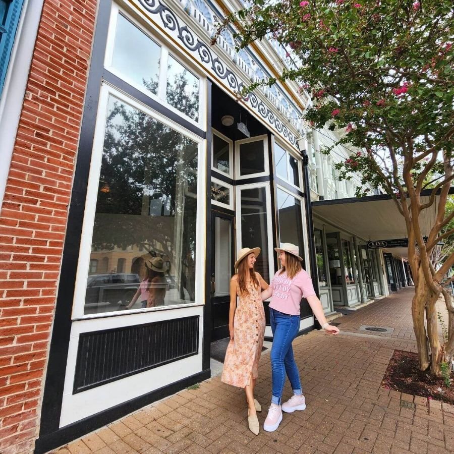 Two woman half hug on a sidewalk in downtown Georgetown Texas