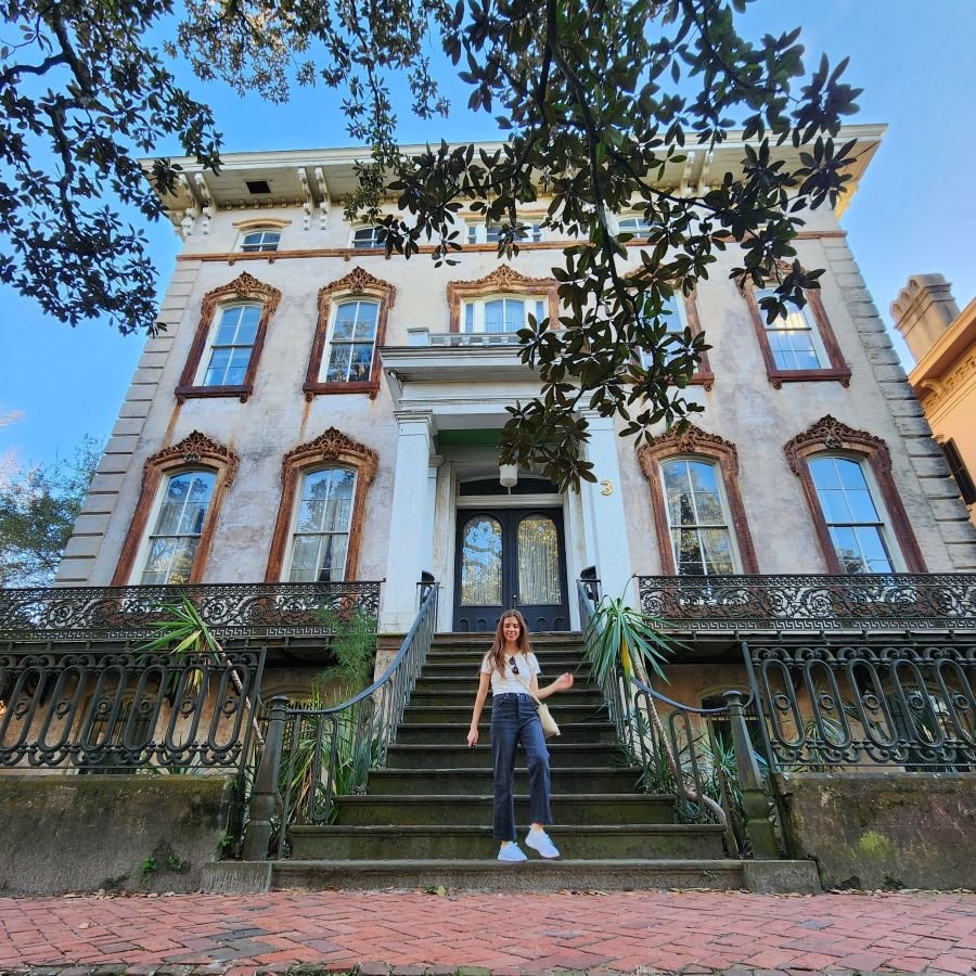 A woman walks down steps in from of a historic mansion on a Savannah girls trip
