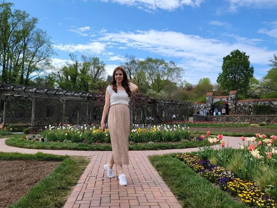 A woman in a floral skirt walks in a garden in Asheville, North Carolina