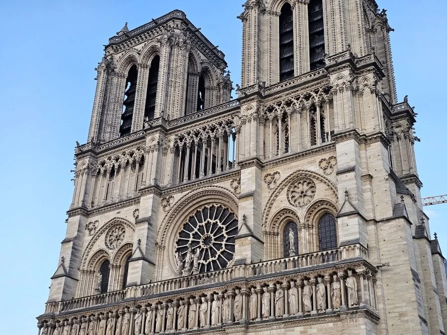 Closeup of the top half of the Notre Dame Cathedral in Paris with two towers and sculptures