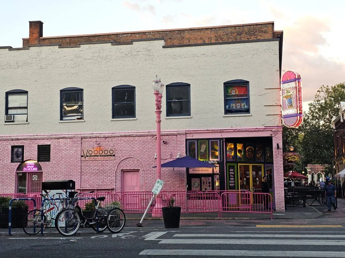 The pink brink Voodoo Donut building on a street corner in Portland, Oregon