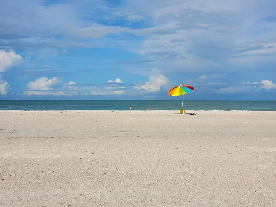 An umbrella sits on a beach of white sand in Florida