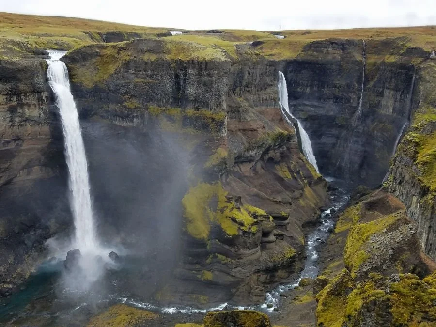 Two tall waterfalls flow into a deep canyon in Iceland