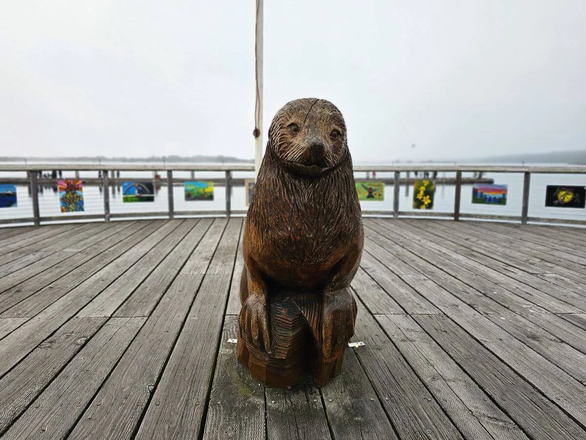 A wooden seal sculpture on a wooden dock on a harbor in Oregon