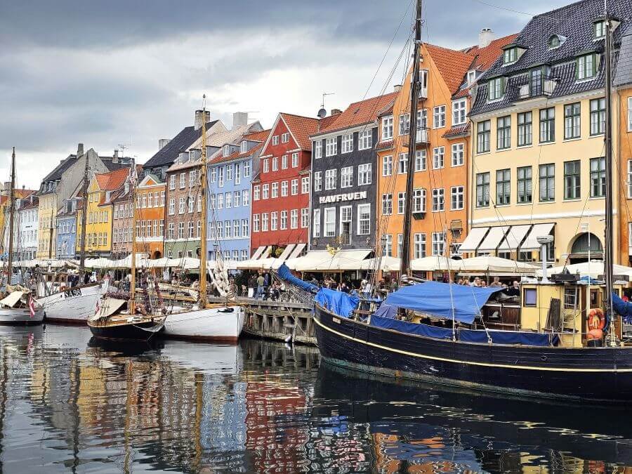 Colorful building fronts line a canal waterway with boats along the shore in Copenhagen.