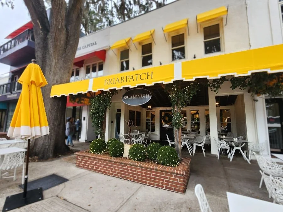 A cafe front with yellow awning and umbrellas in Winter Park Florida.
