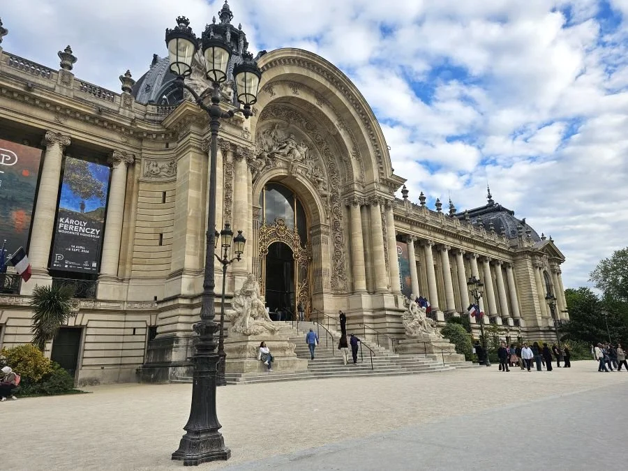 The front of Petit Palais in Paris has columns, a golden door and statues.