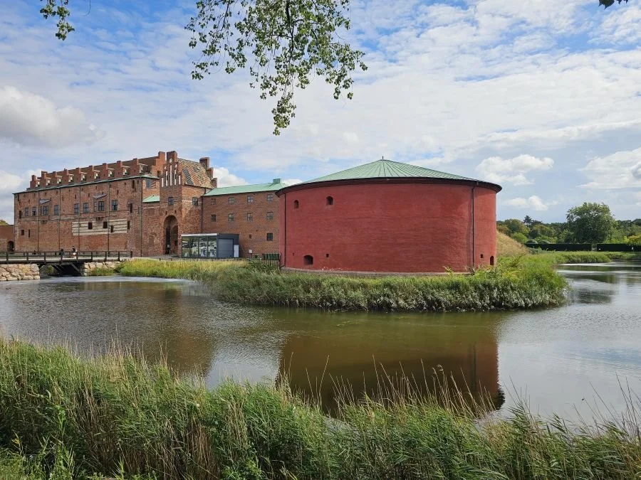 The Malmo castle with a round red section on the right and a moat full of water below.