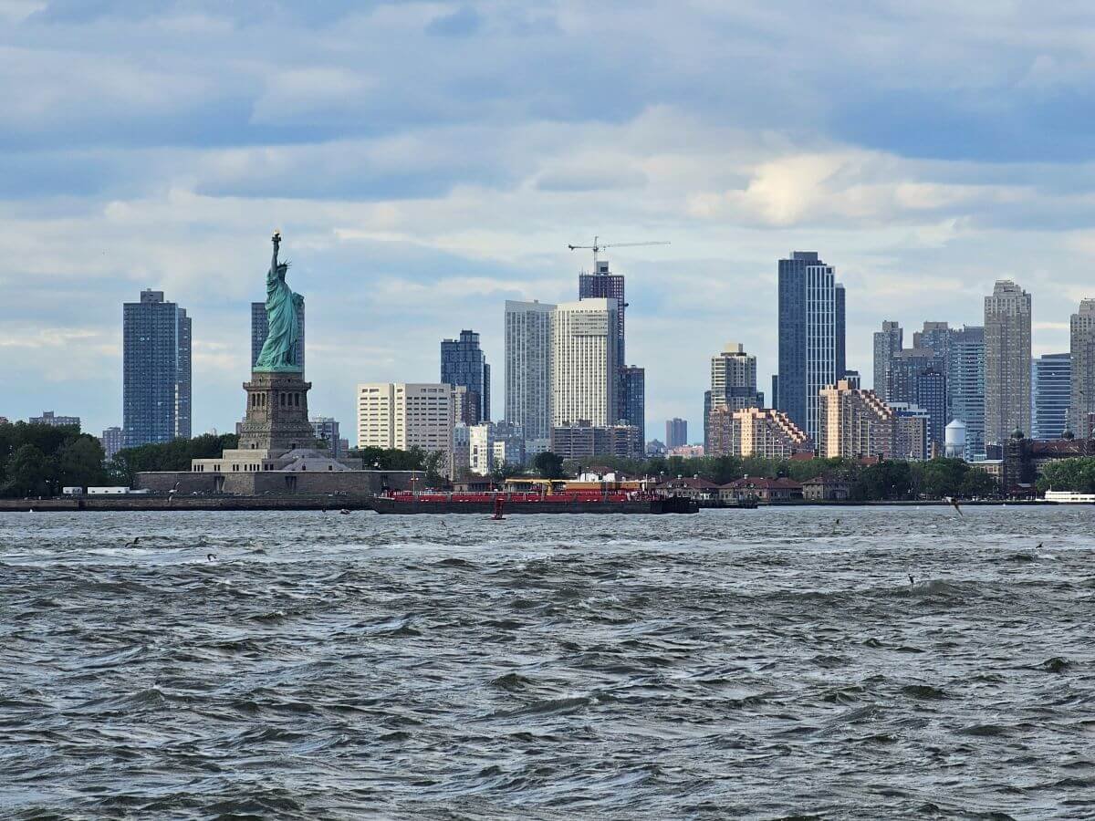 The Statue of Liberty with the New York Skyline behind it on the water