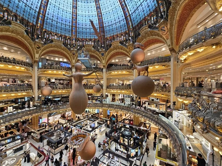 The inside of Galleries Lafayette with art hanging from the central atrium