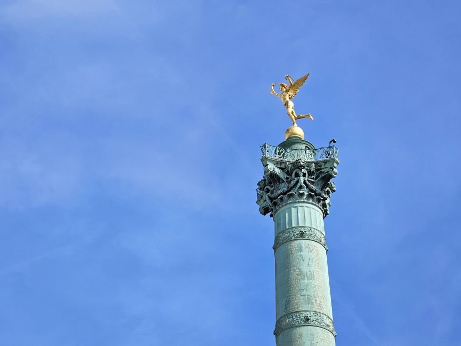 A Paris statue with a green column and gold figure on top