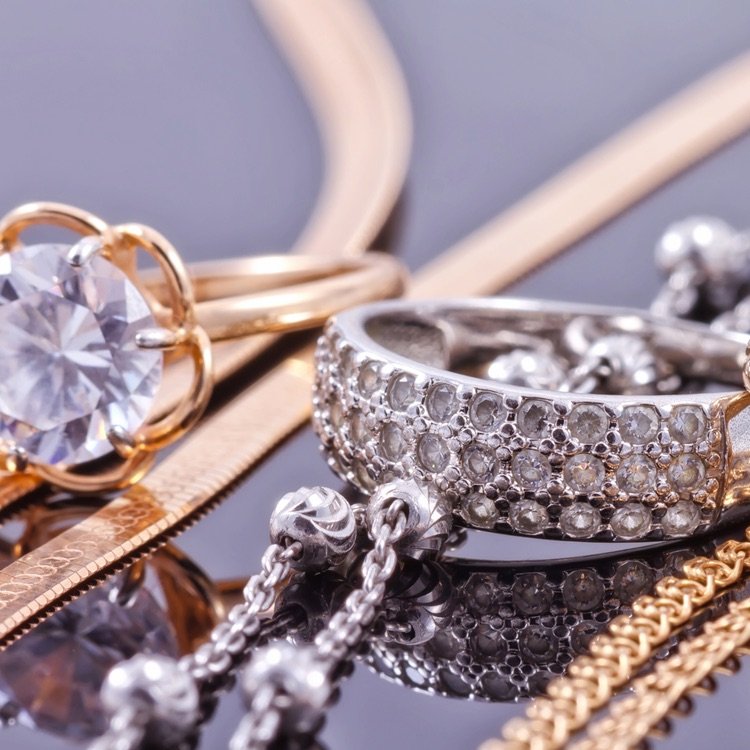 Close-up of various jewelry items including a large diamond ring, a glittering diamond-encrusted bracelet, and gold chains.