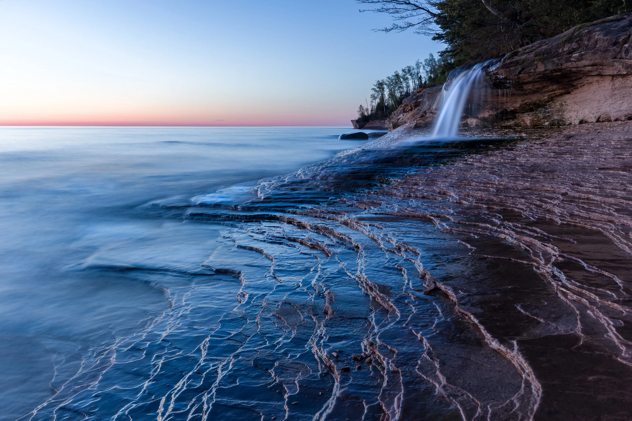 long exposure of a waterfall and colorful sunset at Miner's Beach in the Upper Peninsula of Michigan