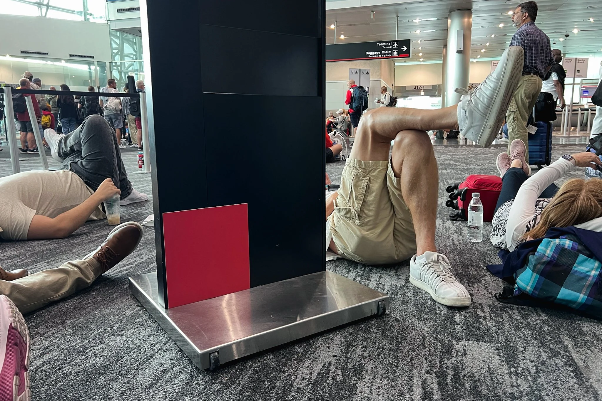 Travelers resting on the floor of an airport during a delay.