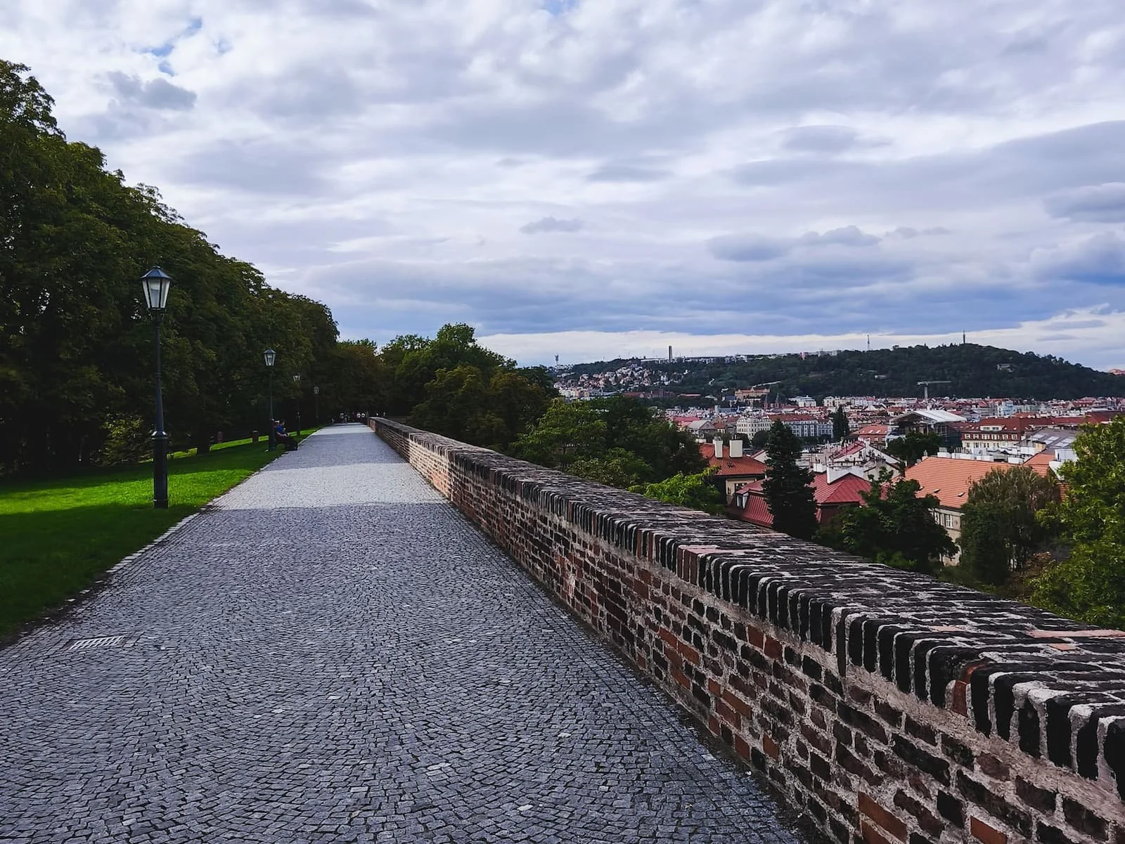 Walkway along the historic Vyšehrad ramparts with greenery and views over Prague.