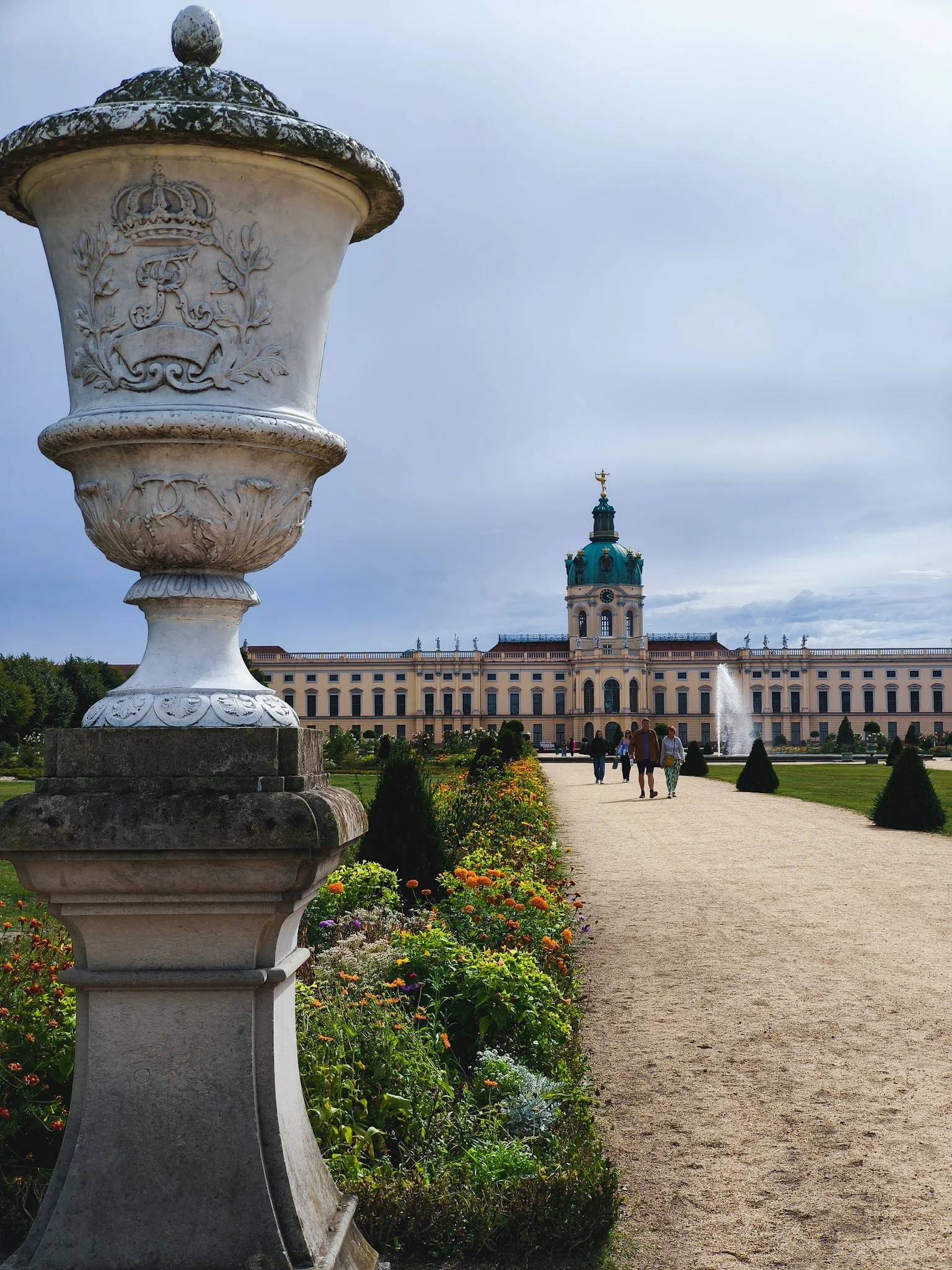 View of Charlottenburg Palace in Berlin from its gardens, with a decorative stone urn and landscaped grounds in the foreground.