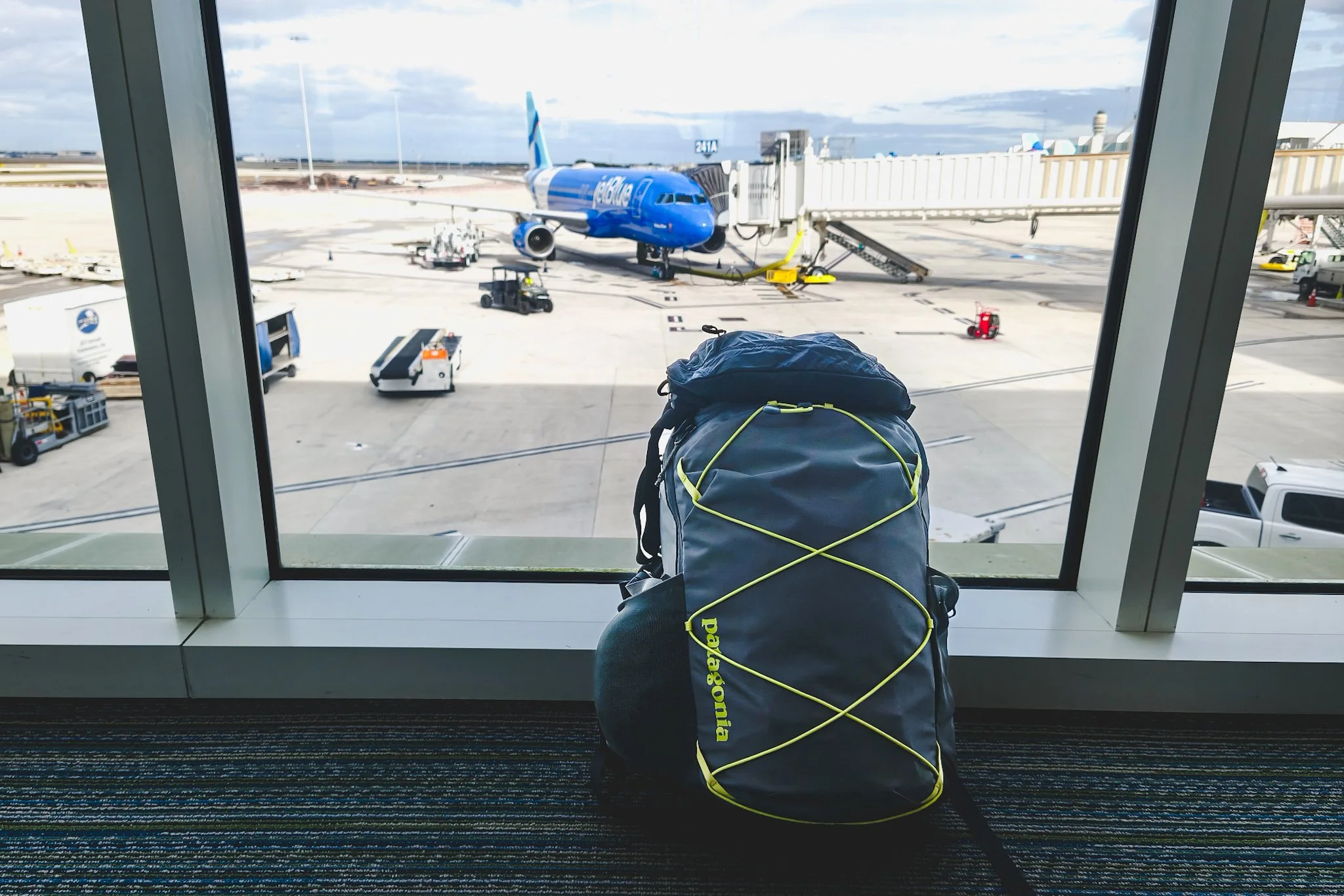 A grey Patagonia Refugio leaning against an airport window.