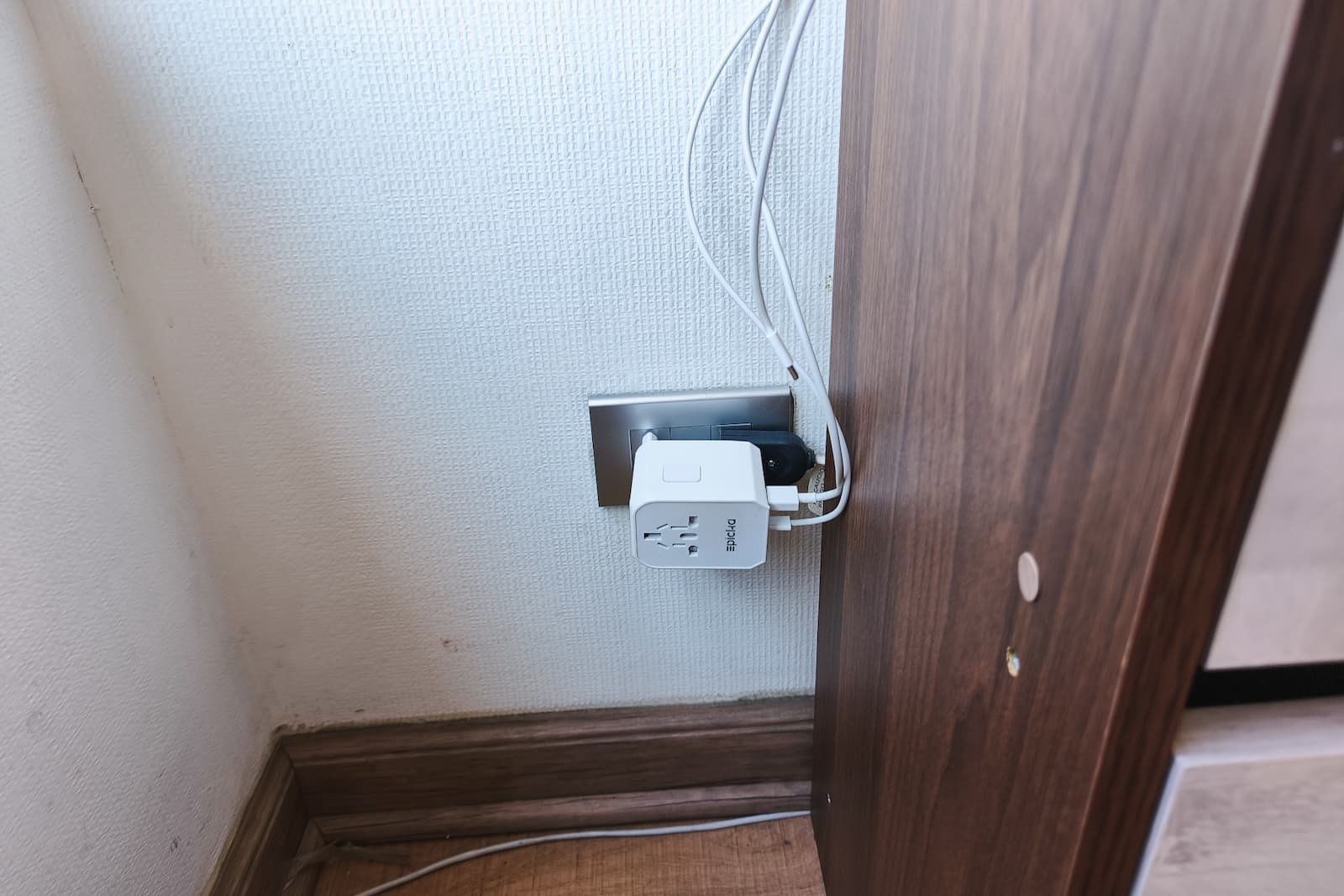 Universal travel adaptor plugged into a wall outlet with devices charging.