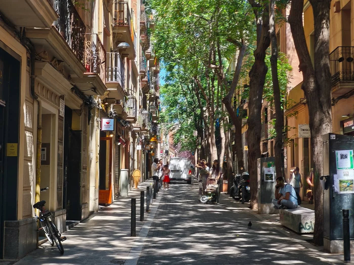 Tree-lined Carrer de Verdi with balconies and neighborhood buildings in Gràcia, Barcelona