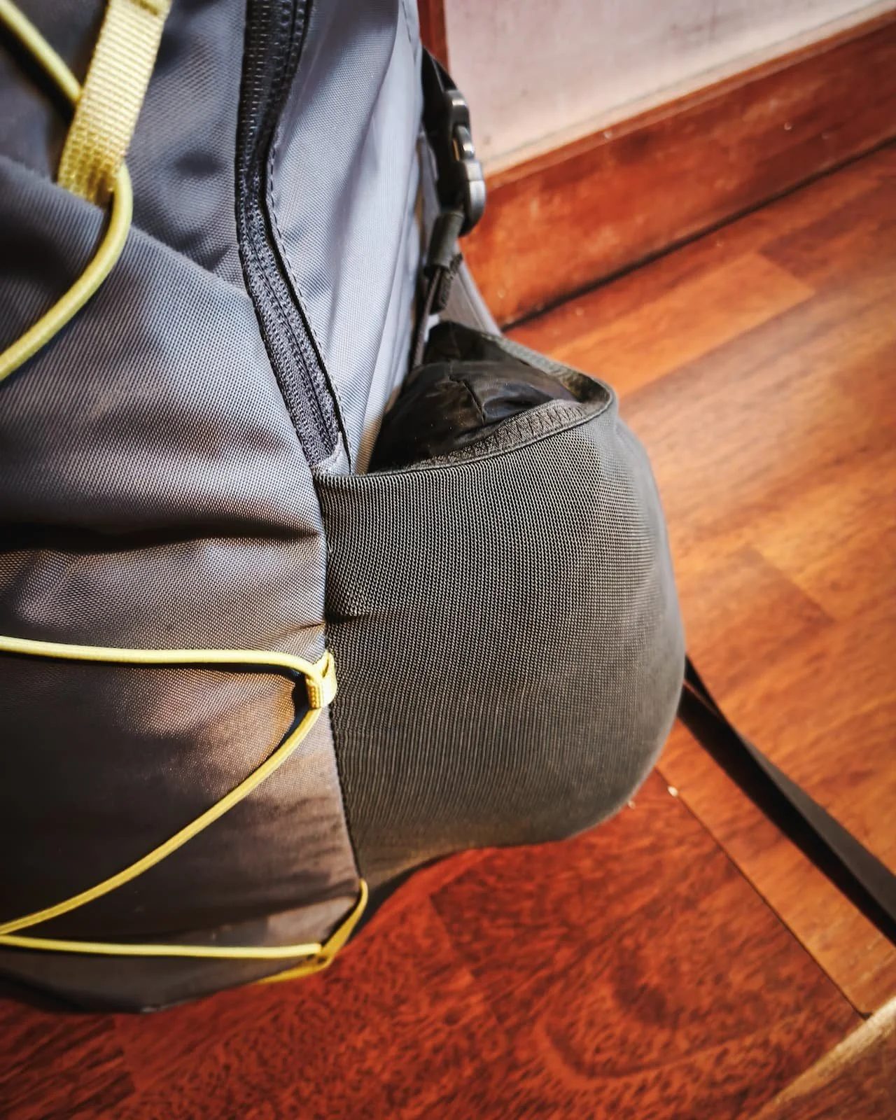 Lightweight insulated jacket stored in the outer mesh pocket of a backpack.