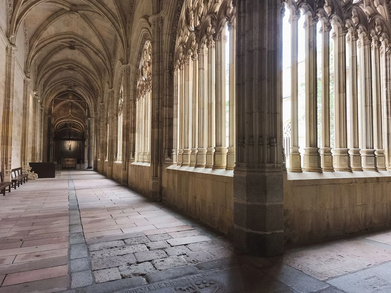 Cloister inside Segovia Cathedral with stone arches and light coming through the windows.