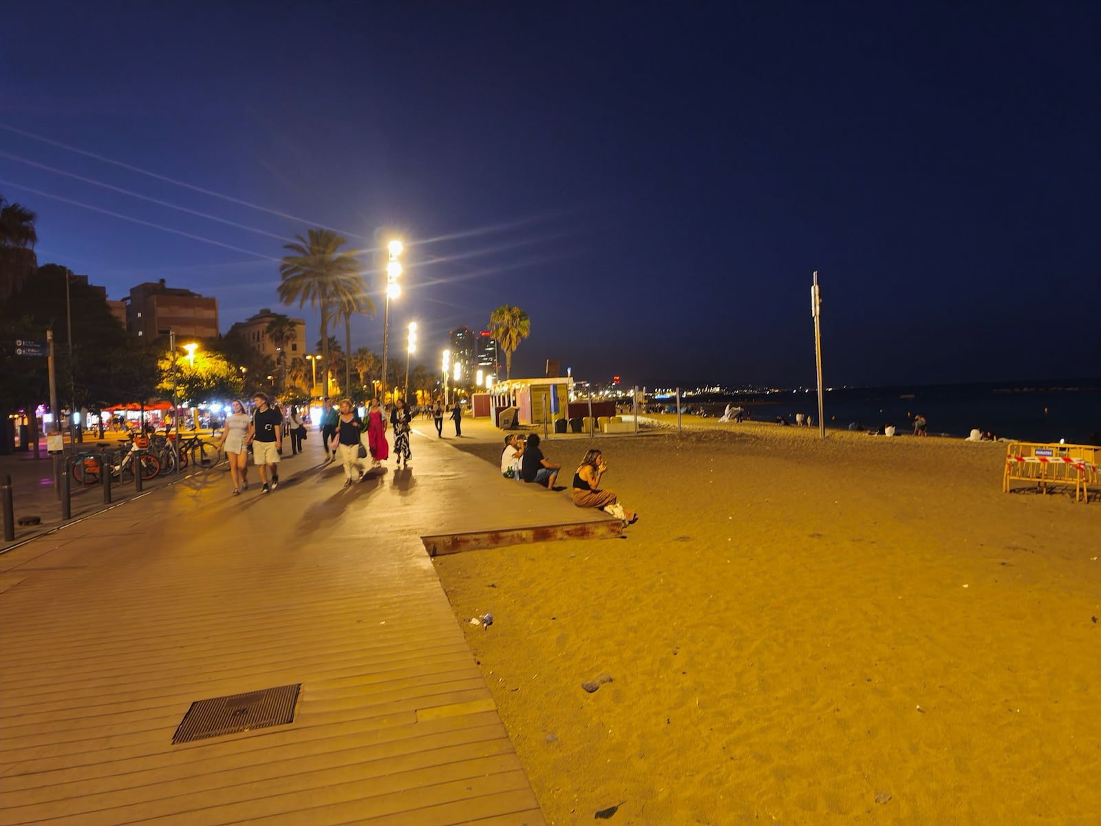 Evening view of the illuminated waterfront promenade and beach in Barceloneta