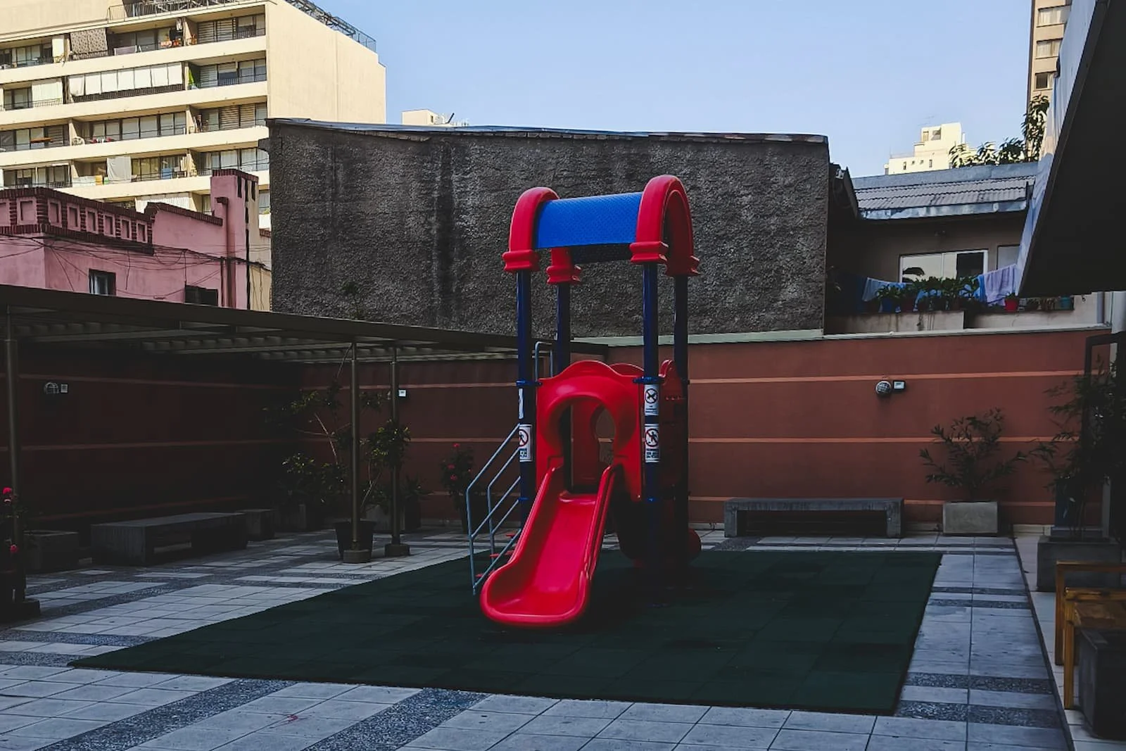 Empty playground courtyard with a small slide and rubber flooring in an urban apartment complex
