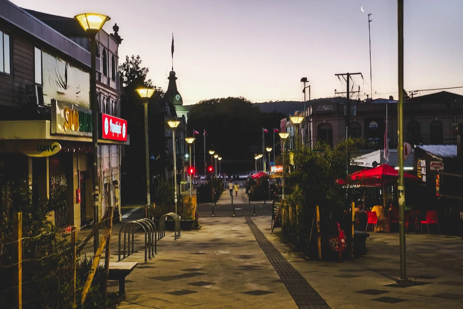 Paseo Libertad pedestrian street lit by street lamps in the evening in downtown Valdivia, Chile.