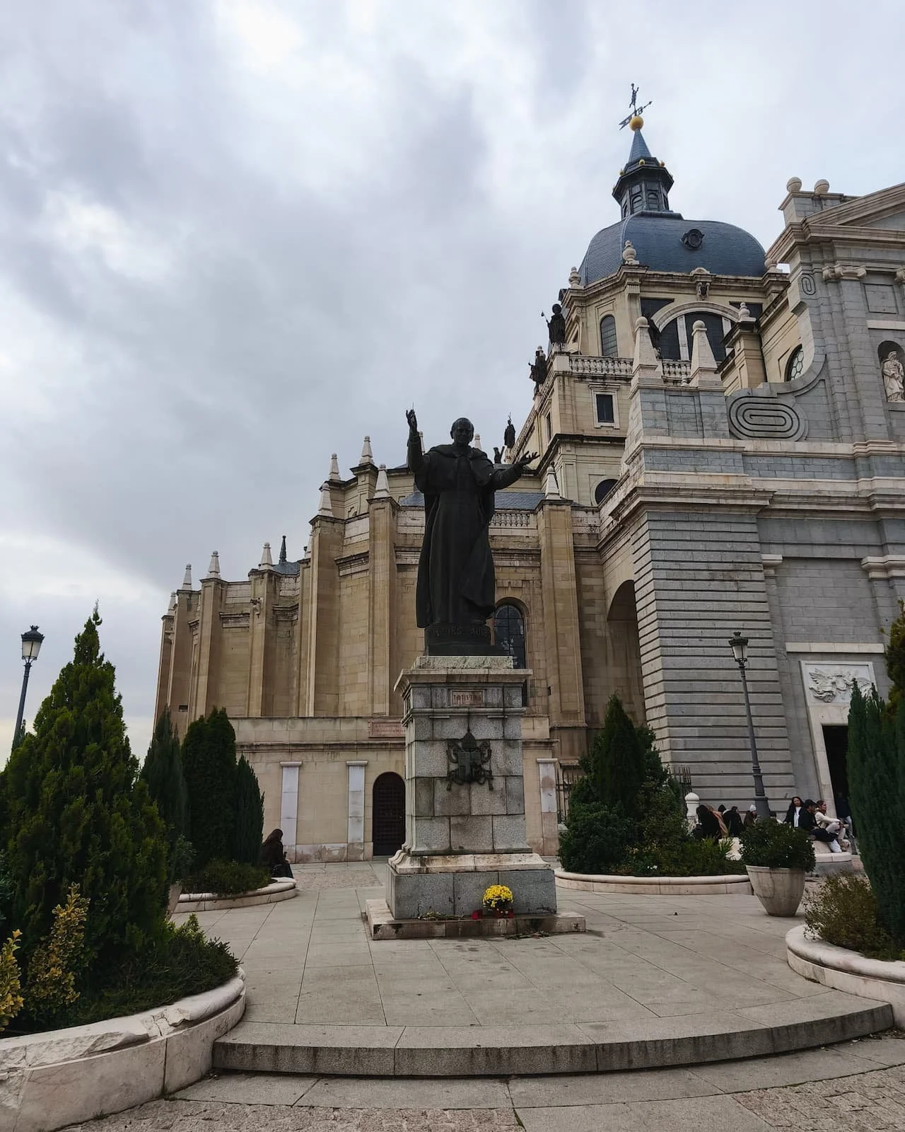 Exterior of Almudena Cathedral in Madrid with a statue in the foreground.
