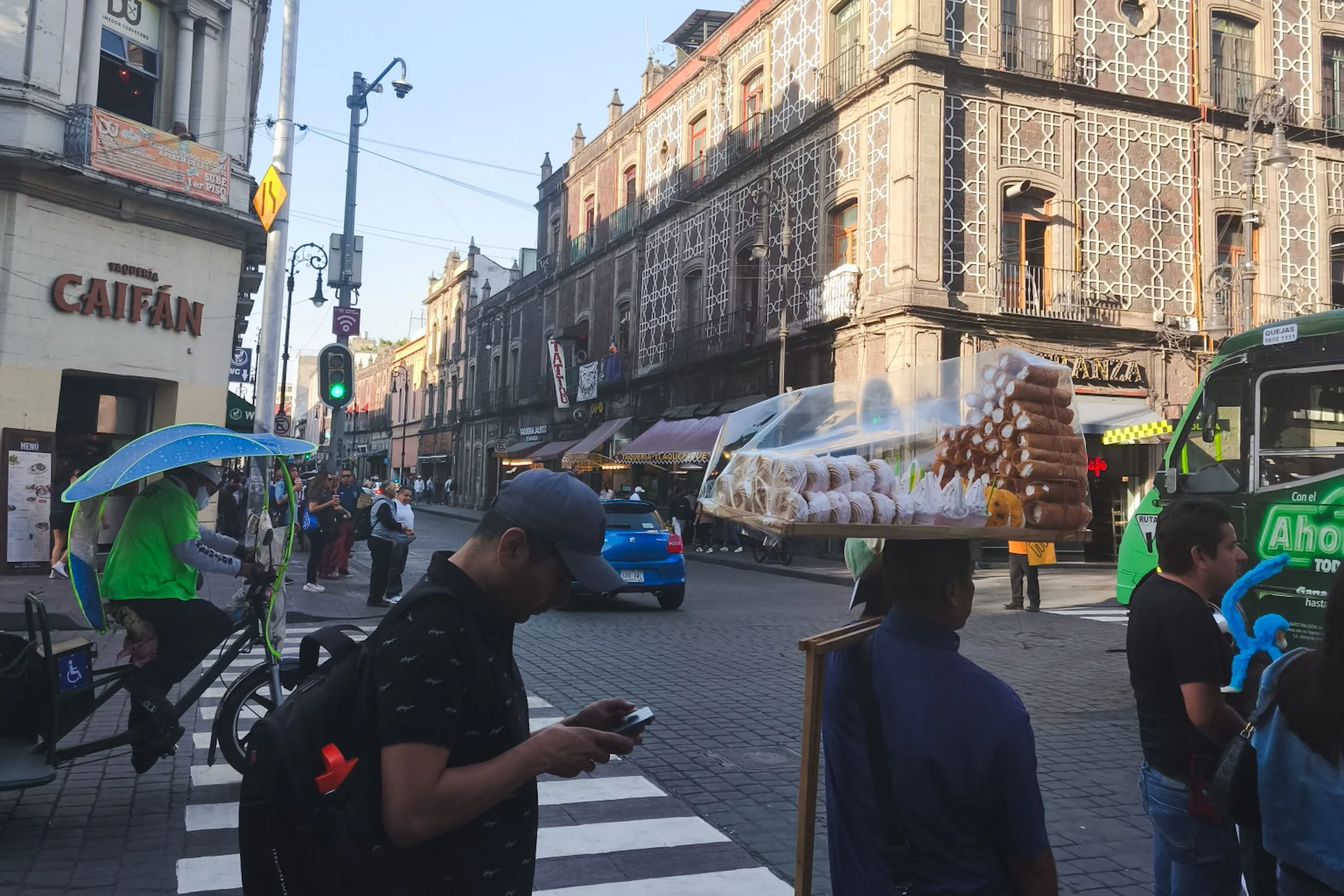 Street scene in Mexico City, Mexico with pedestrians and a vendor carrying pastries on his head.