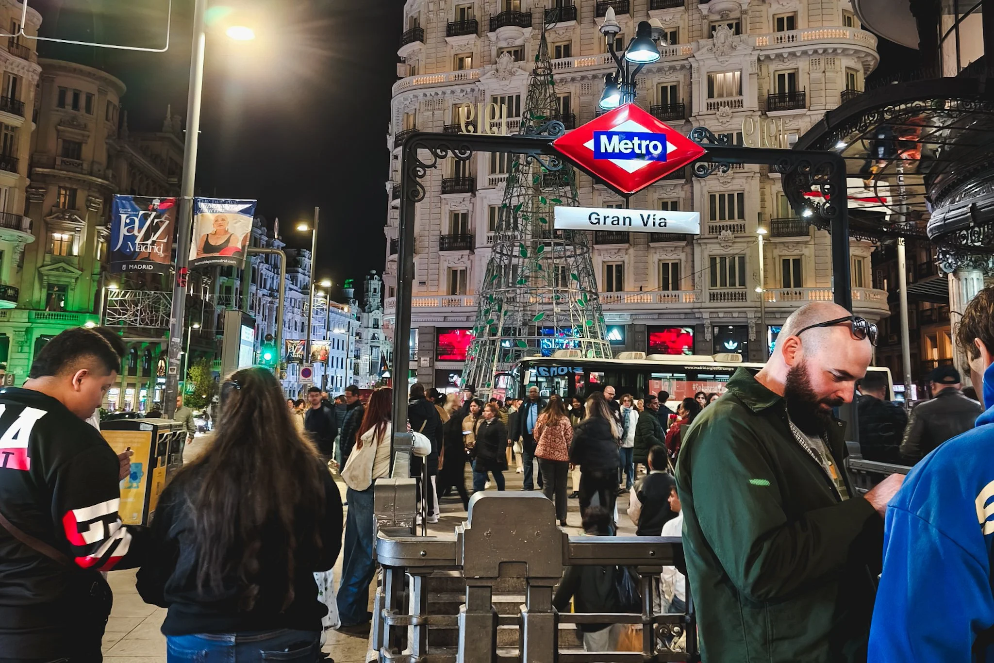 Busy nighttime street scene on Gran Vía in Madrid, Spain with crowds, lights, and traffic.