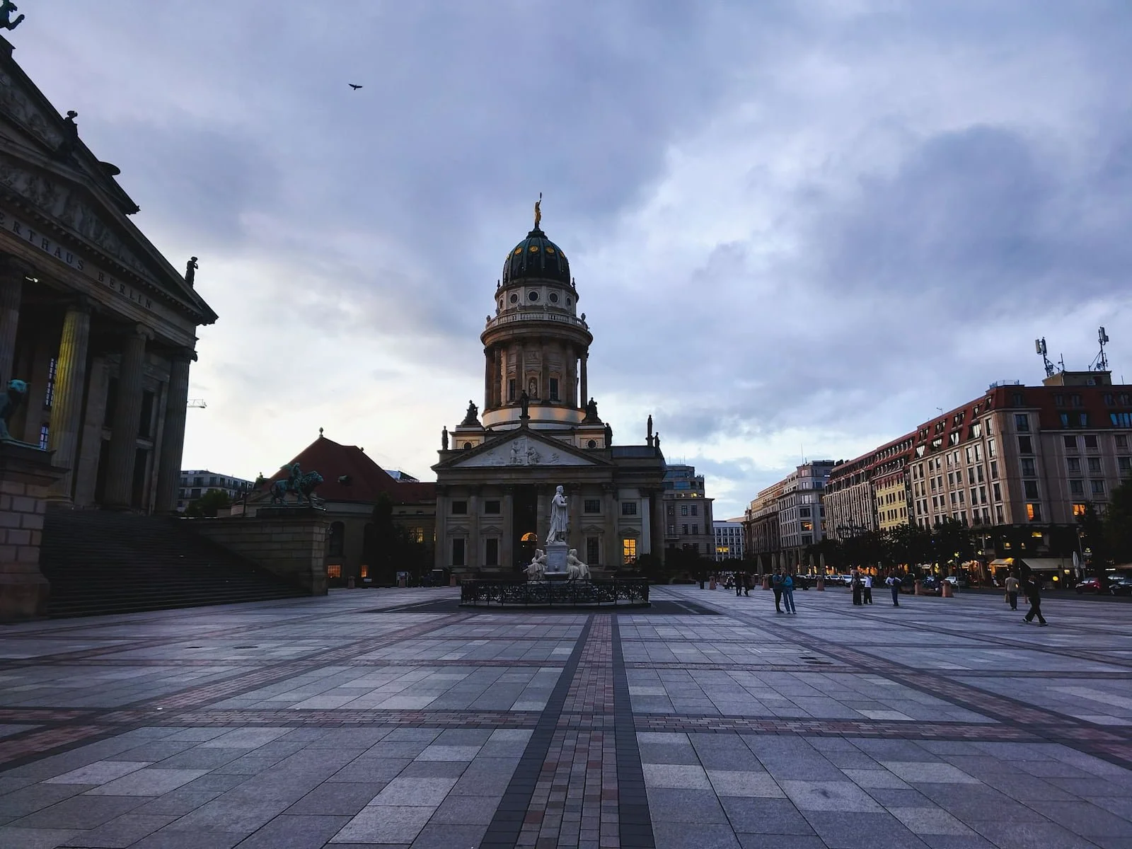 Wide paved square at Gendarmenmarkt in Berlin, with a historic domed cathedral and surrounding buildings.