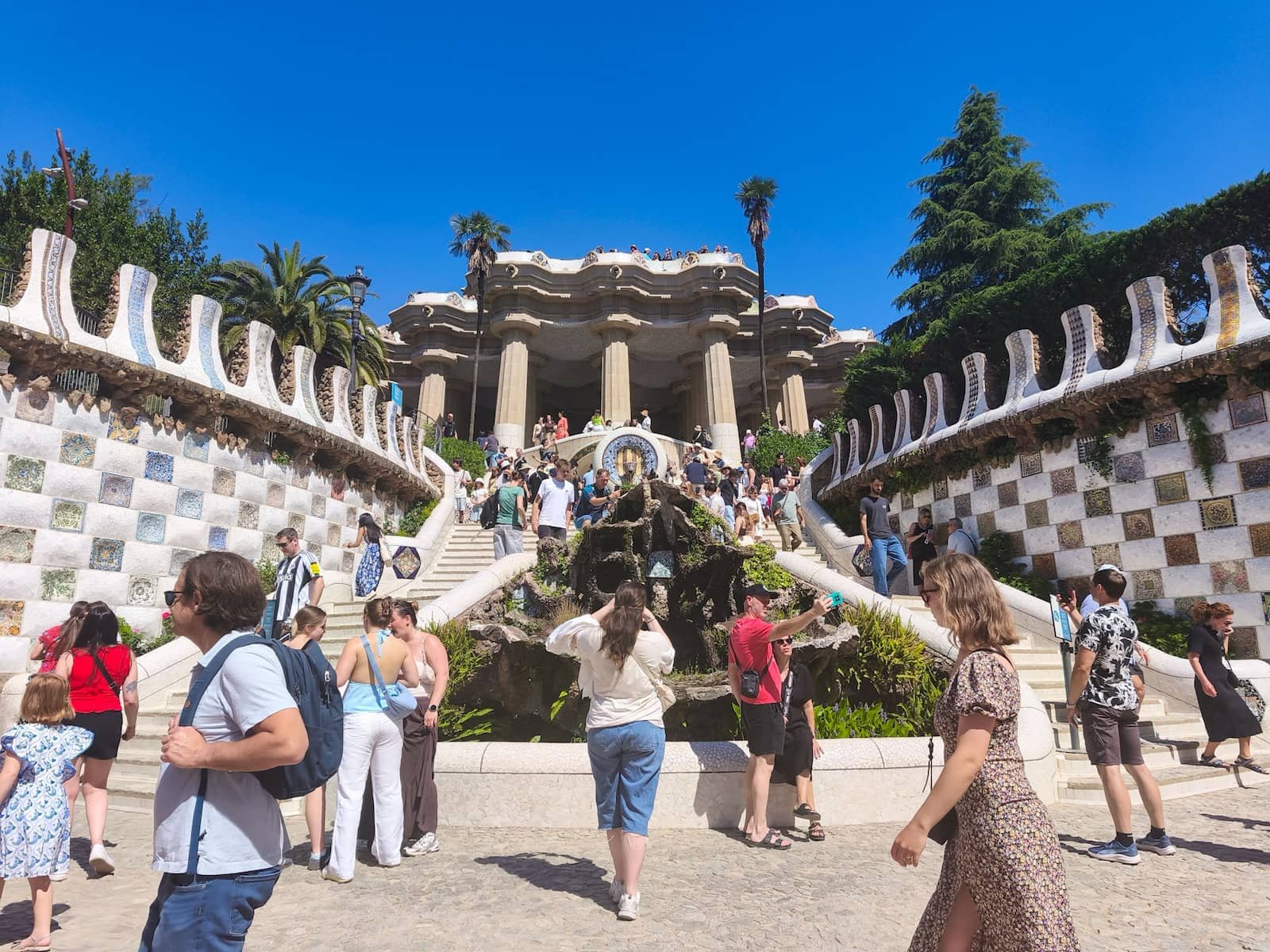 Visitors walking around the monumental staircase at Park Güell