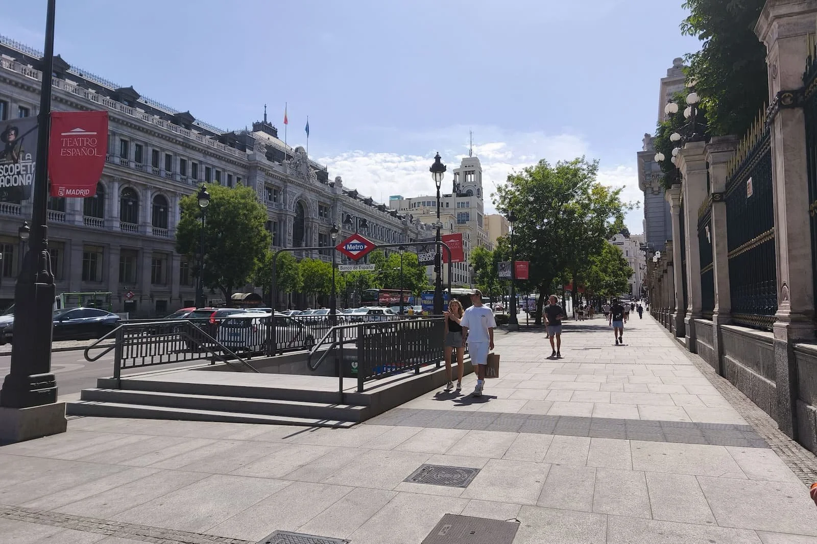 Street scene in Madrid with warm lighting, buildings, and people walking.