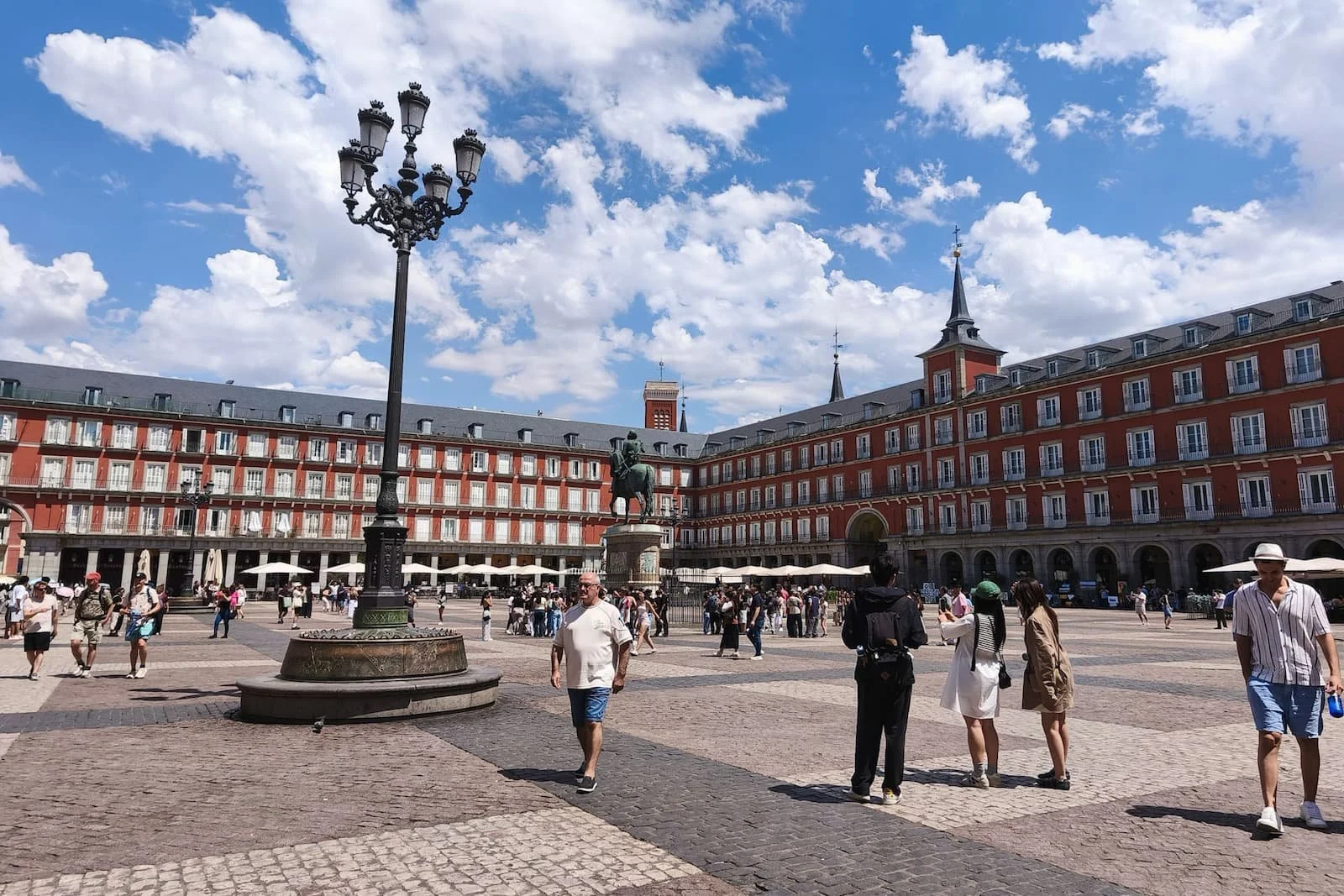 Large historic square Plaza Mayor in Madrid with surrounding buildings and people walking.