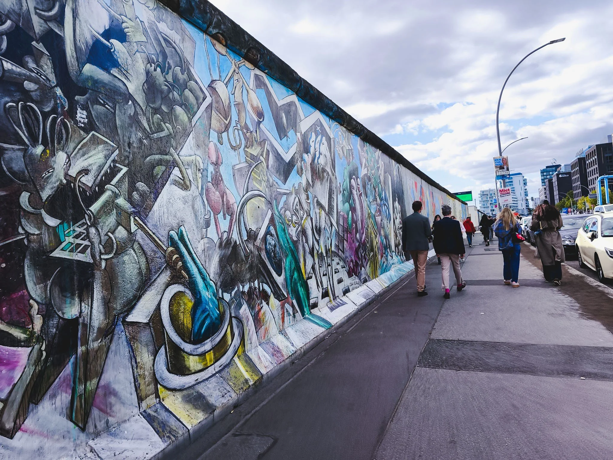 Long stretch of the East Side Gallery in Berlin, with colorful murals covering the surviving Berlin Wall.