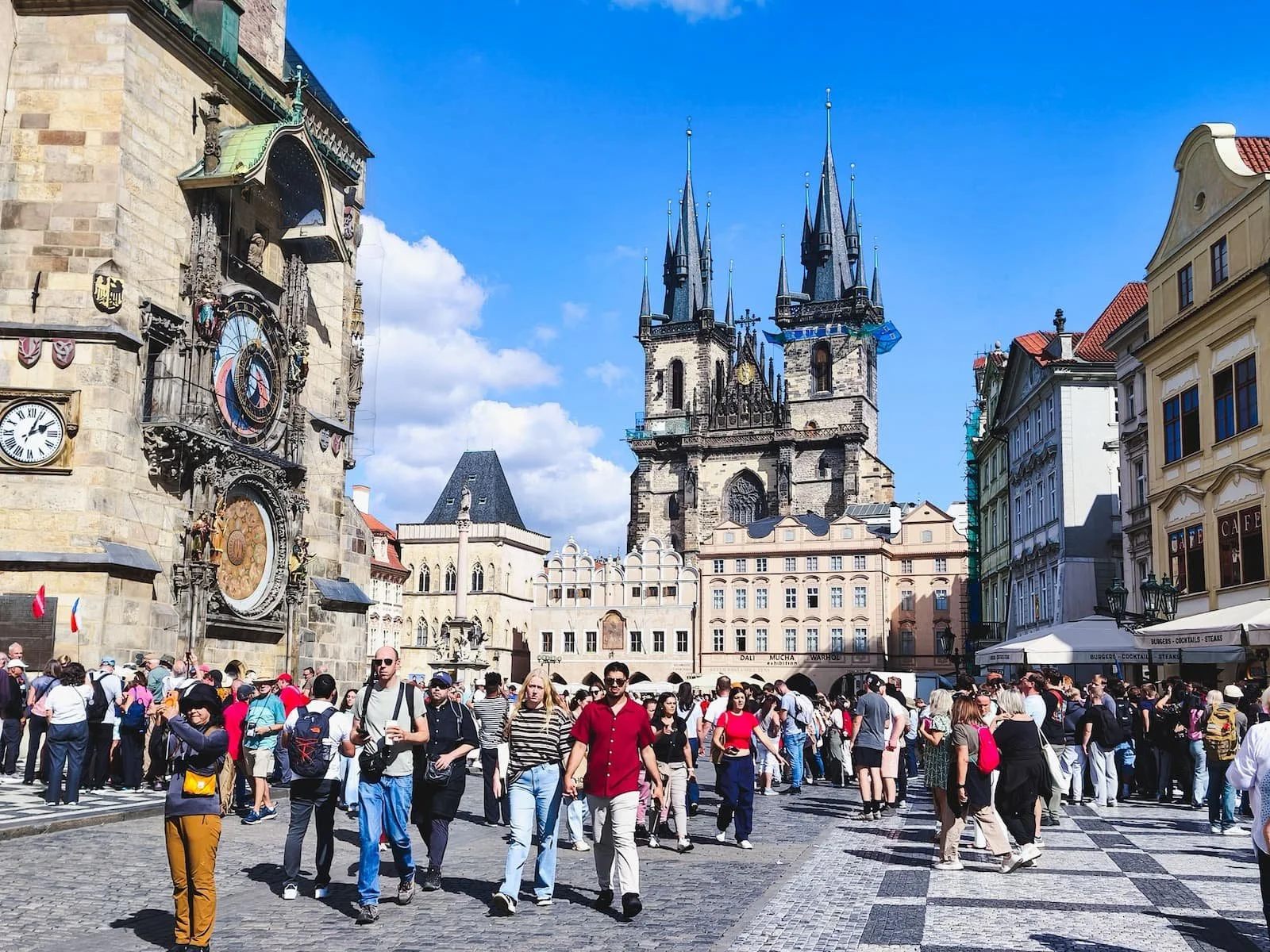 Prague's Astronomical Clock on the Old Town Hall, with the Church of Our Lady before Týn and visitors in Old Town Square.